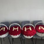 Ваше имя из белых роз на фоне красных роз в больших корзинах